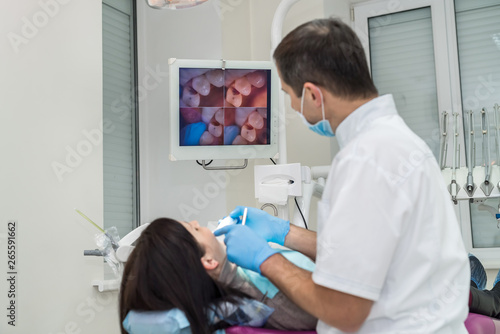 Dentist examining patient's teeth with oral camera