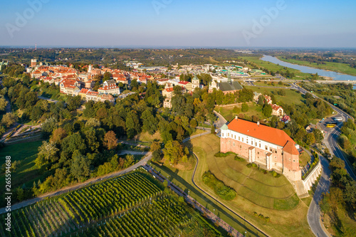 Sandomierz, Poland. Medieval castle in front, old town with town hall tower,  gothic cathedral and Vistula river with bridges in the background. Aerial view in sunset light