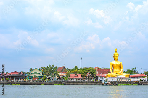 Big Buddha golden and the house behind Chao Phraya River. Background sky and clouds at Wat Bang Chak in Nonthaburi , Thailand.