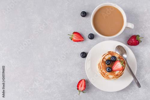 pancakes with berries and a cup of fresh coffee  grey background  free space