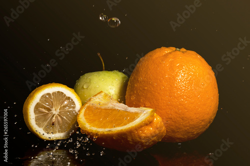 Apples and oranges fruits with drops and splashes of water on a black background