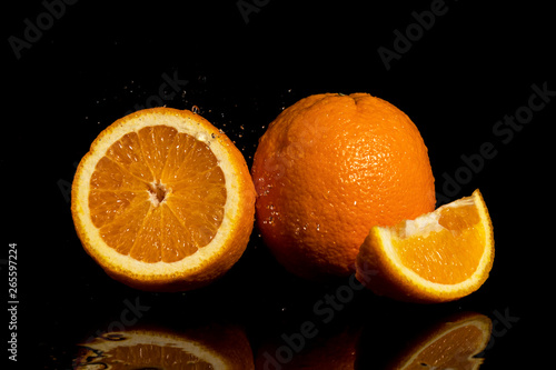 Oranges fruit with drops and splashes of water on a black background
