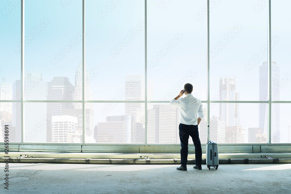 Businessman talking on the phone against a large window Businessman talking on the phone against a large window