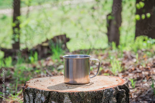 Metal mug on background of forest