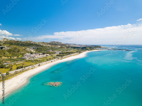 Vista aerea della città di Roccella Ionica o Jonica in Calabria, con il porto delle Grazie, il castello Carafa e la bellissima spiaggia sabbiosa con il mare Mediterraneo blu.  © Polonio Video