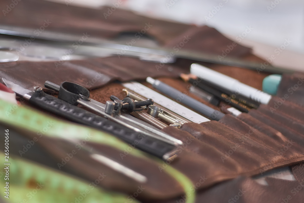 Leather crafting DIY tools and templates on workbench. Instruments in brown leather case.