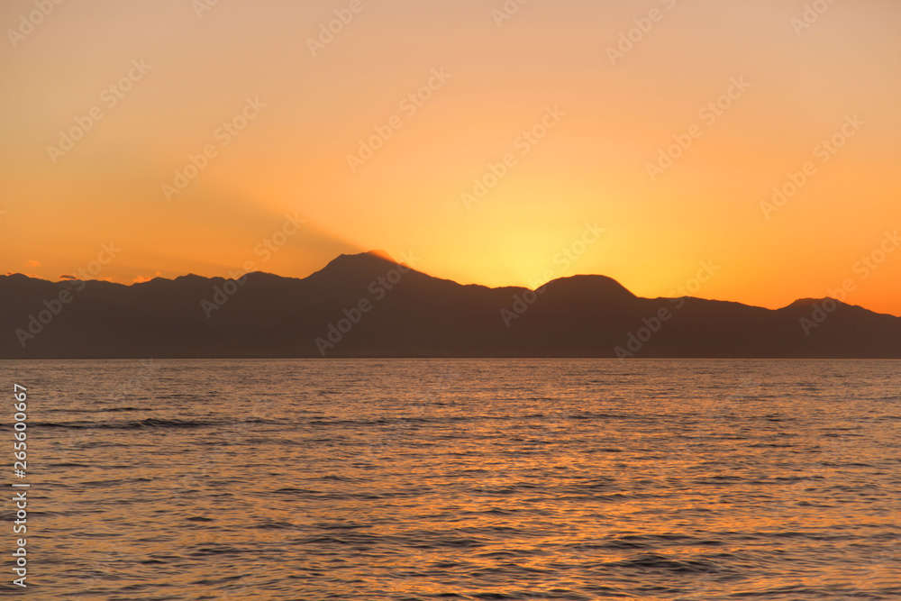 sunset dusk with mountain silhouette and orange color reflection in the water sea a tranquil Background photography