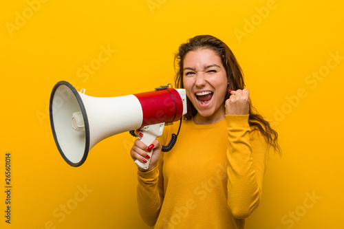 Young european woman holding a megaphone cheering carefree and excited. Victory concept.