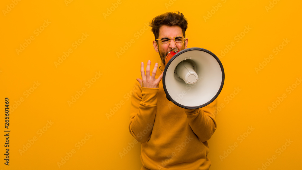 Young man holding a megaphone very scared and afraid Young man holding a megaphone very scared and afraid