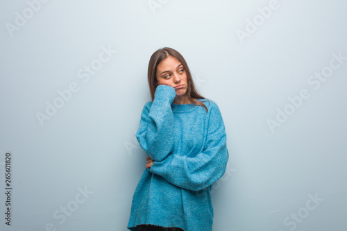Young pretty woman wearing a blue sweater thinking of something, looking to the side © Asier
