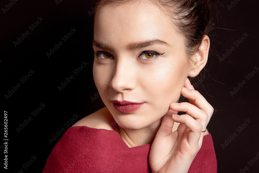 Close-up portrait of a woman with classic make-up with a black arrow and bare lip over her shoulders on a black background Close-up portrait of a woman with classic make-up with a black arrow and bare lip over her shoulders on a black background