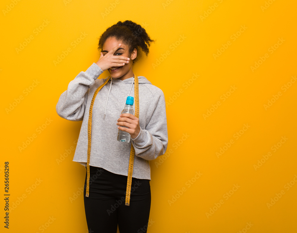 Young fitness black woman embarrassed and laughing at the same time.Holding a water bottle. Young fitness black woman embarrassed and laughing at the same time.Holding a water bottle.