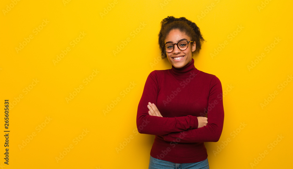 Young black african american girl with blue eyes crossing arms, smiling and relaxed