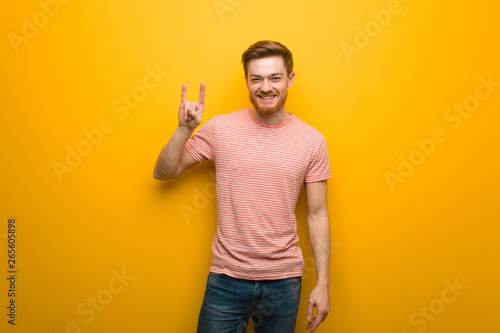 Young redhead man doing a rock gesture