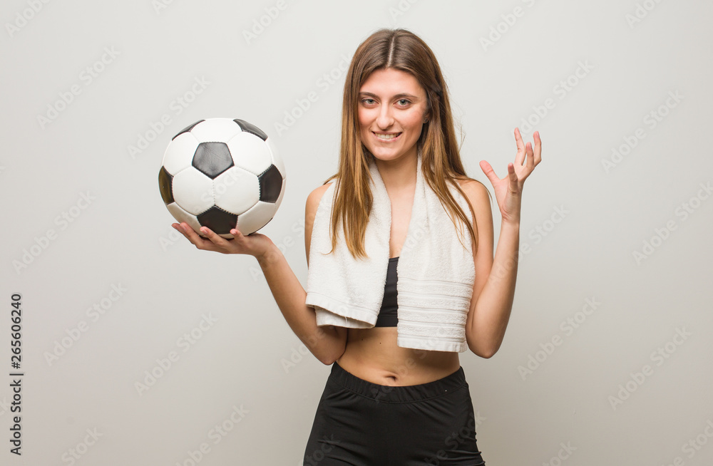 Young fitness russian woman angry and upset. Holding a soccer ball.