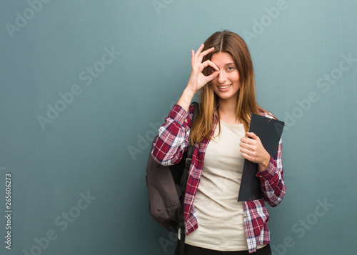 Young student russian woman confident doing ok gesture on eye