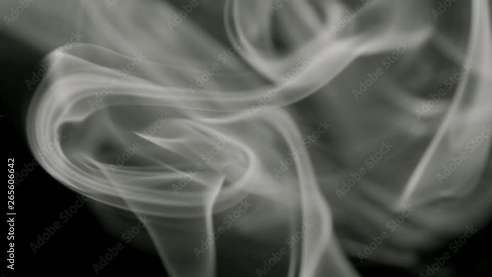 Thin trickle of gray smoke slowly rising graceful twists up on black background. Black and white smoke blowing from bottom to top. Closeup Thin trickle of gray smoke slowly rising graceful twists up on black background. Black and white smoke blowing from bottom to top. Closeup
