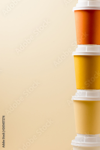 colorful disposable cups with white caps isolated on beige
