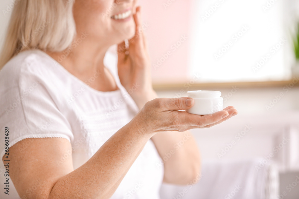 Fototapeta premium Mature woman applying facial cream at home