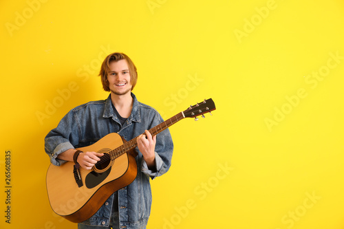 Handsome young man playing guitar on color background © Pixel-Shot