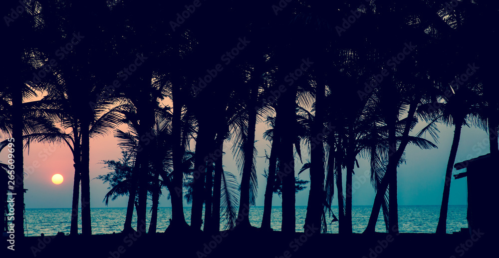 A sunset over a ocean with palm trees silhouettes