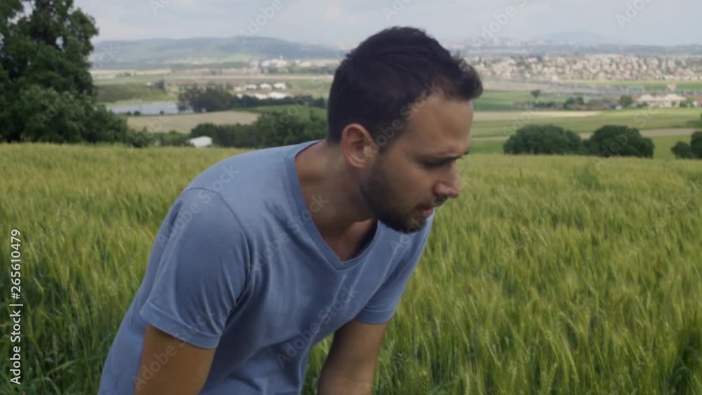 Young jogger runs, stops to take a breath and then continues to run in rural green scenery Young jogger runs, stops to take a breath and then continues to run in rural green scenery