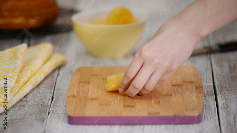 Hands cutting pineapple on a cutting board on a wooden table. Hands cutting pineapple on a cutting board on a wooden table.