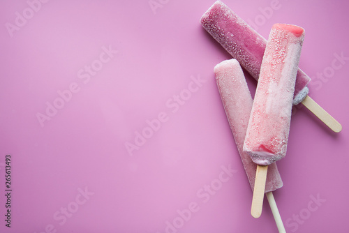 Bright fruit ice cream on a stick on a pink background. Frozen fruit ice. Summer mood. Cooling dessert in hot weather. Favorite delicacy for children. Homemade raspberry, strawberry, watermelon ice