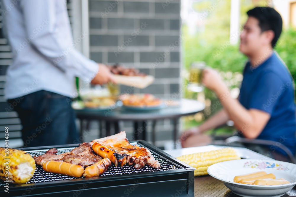 Group of friends Two young man enjoying grilled meat and raise a glass of beer to celebrate the holiday festival happy drinking beer outdoors and enjoyment at home