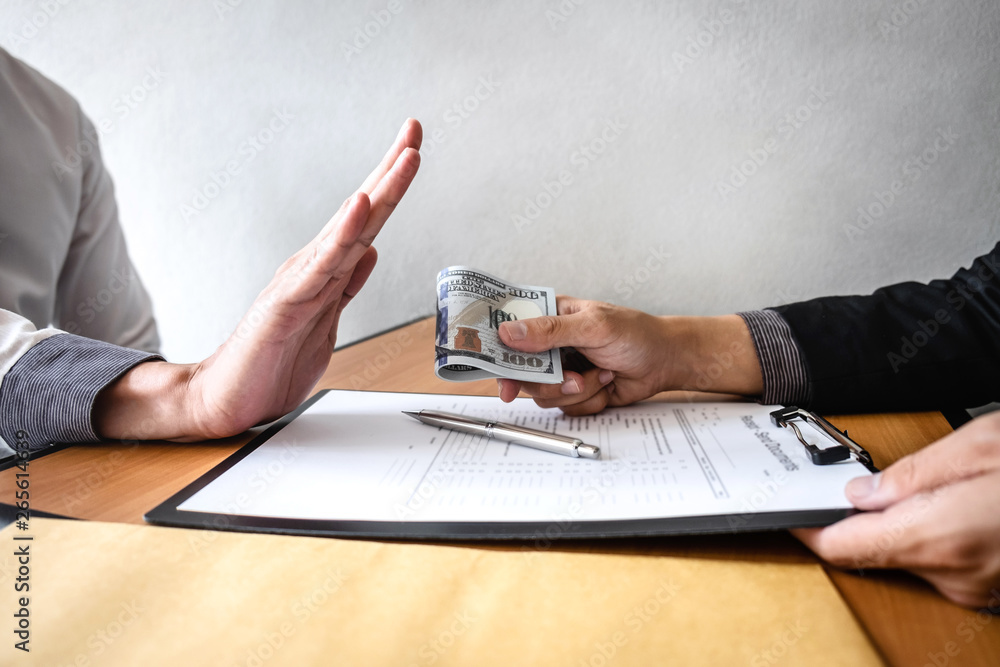 Fototapeta premium Anti bribery and corruption concept, Business man refusing and don't receive money banknote in envelop offer from business people to accept agreement contract of investment deal