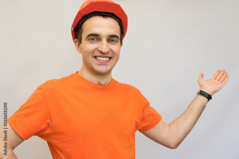 Builder with protective helmet on his head, smiling, shows his hand on the free space Builder with protective helmet on his head, smiling, shows his hand on the free space