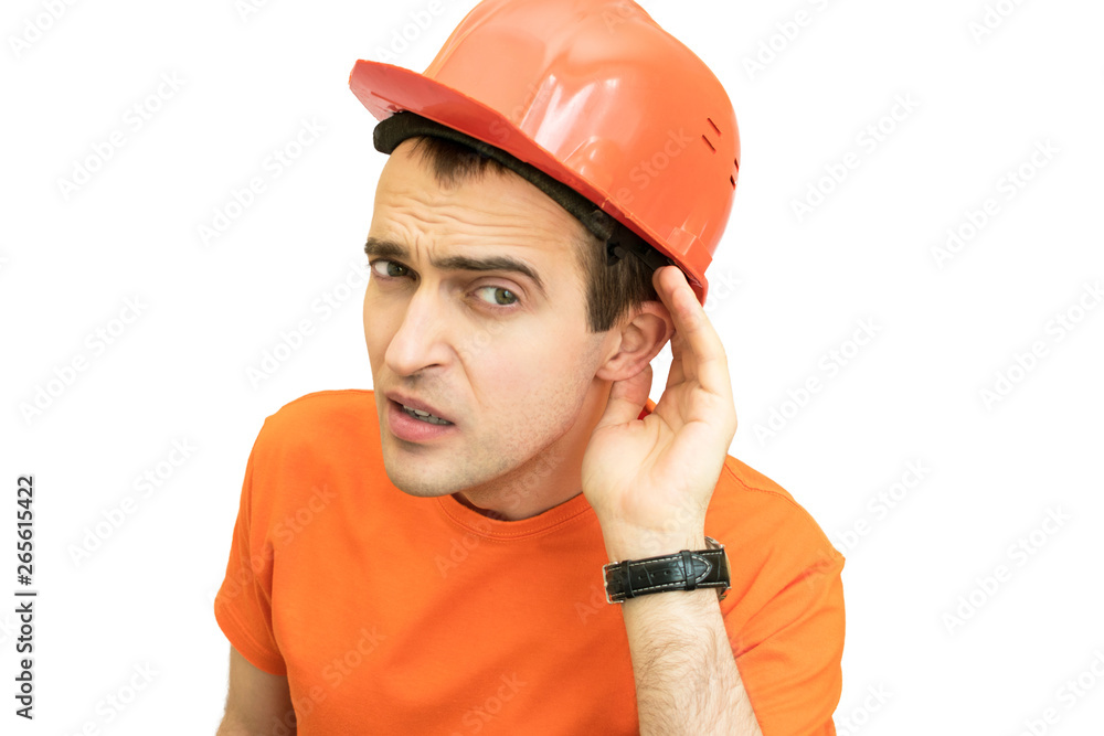 Handsome young guy with protective helmet on his head, can't hear, putting hand around his ear, sad looks at the camera Handsome young guy with protective helmet on his head, can't hear, putting hand around his ear, sad looks at the camera