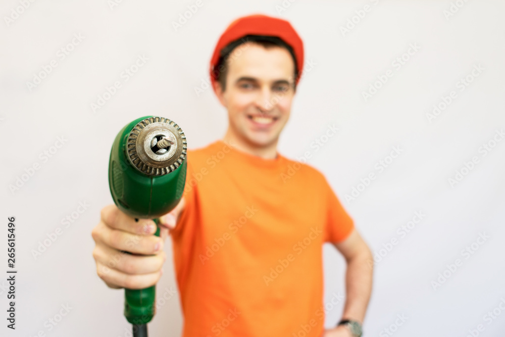 Handsome construction worker with protective helmet on his, directs the camera hand electric drill, looking into the camera, isolated Handsome construction worker with protective helmet on his, directs the camera hand electric drill, looking into the camera, isolated
