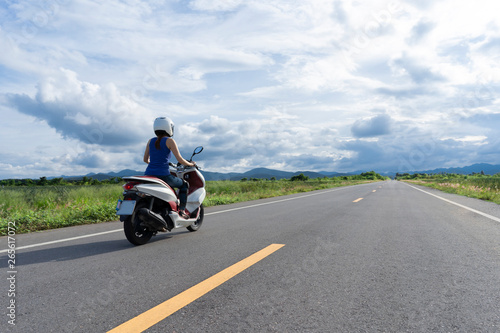 Girl rides motorbike straight to the horisont sunny day clouds sky photo