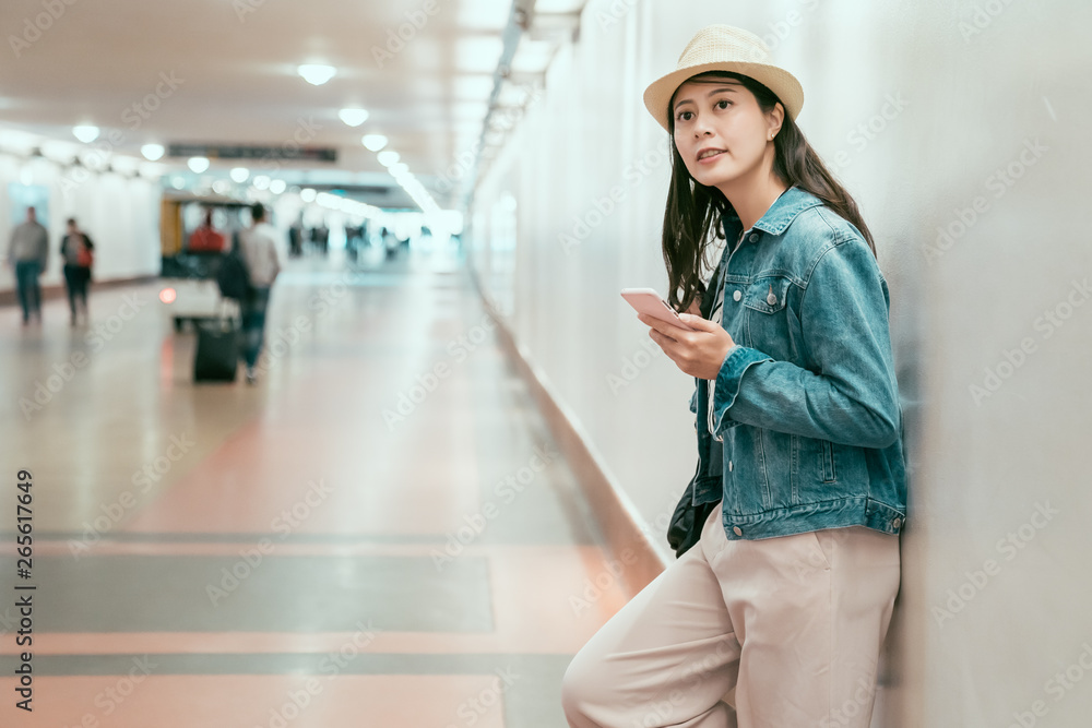 joyful asian local girlfriend leaning on wall in passageway waiting for boyfriend having date. smiling young woman traveler browsing online website relaxing in underpass looking around union station joyful asian local girlfriend leaning on wall in passageway waiting for boyfriend having date. smiling young woman traveler browsing online website relaxing in underpass looking around union station