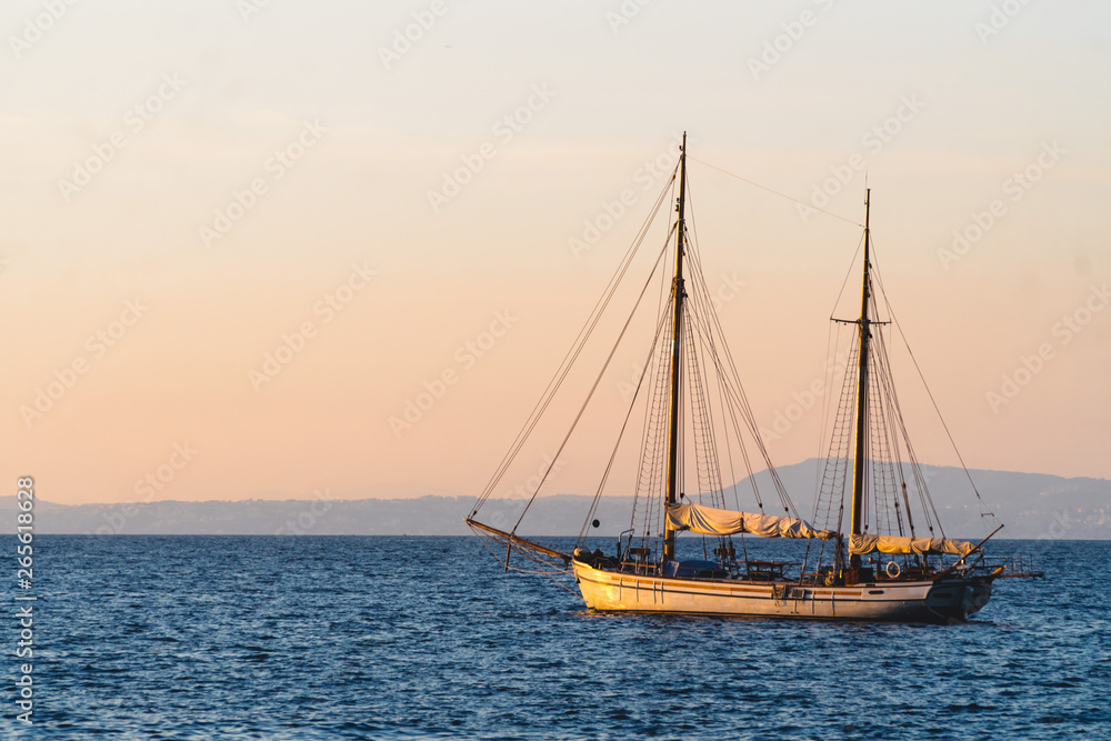 Yacht in the Mediterranean Sea at sunset, luxury travel tour, space for text, summer, ocean surface, water transport, fishing, vacation, two-masted yacht,