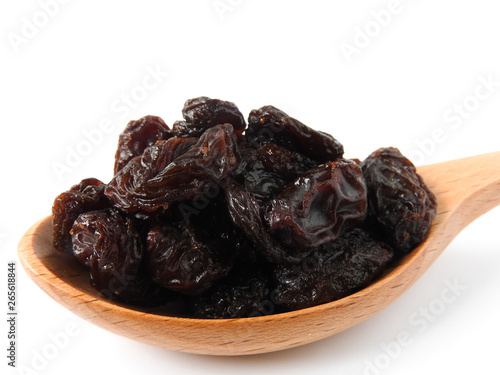 High angle view of raisins on wooden spoon isolated on white background. A raisin is a dried grape Dry food. It tastes sweet and delicious. Texture detail of raisin surface. Food concept.