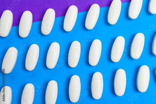 Chaotically scattered white pills on a blue background pattern. White pills background. Texture for design