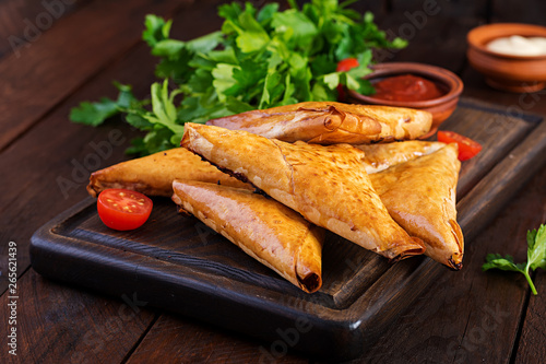 Asian food. Samsa (samosas) with chicken fillet and cheese on wooden background.