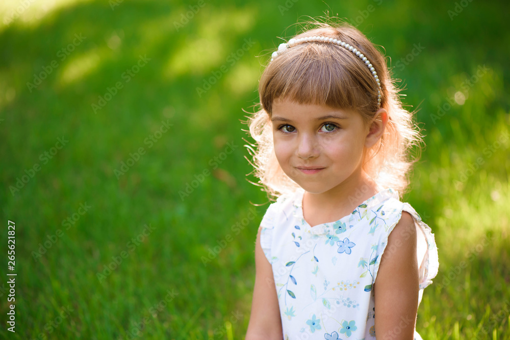 Portrait of a beautiful young little girl in summer park