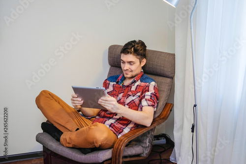 A man uses a digital tablet sitting in a chair.