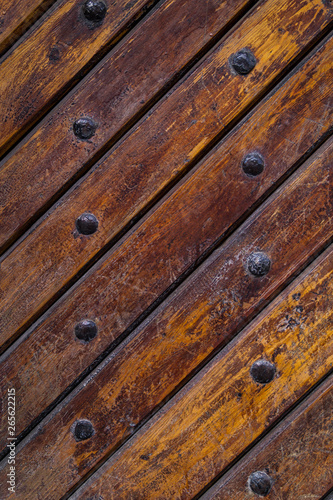 Close up of old vintage wooden door with metal furniture. Brown wooden fence background texture.
