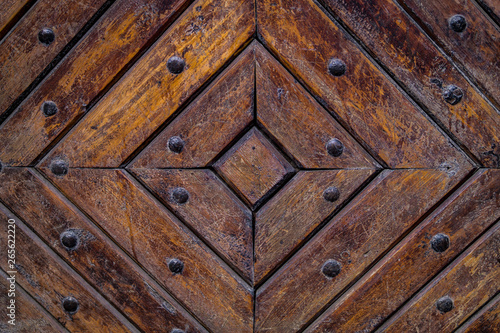 Close up of old vintage wooden door with metal furniture. Brown wooden fence background texture.