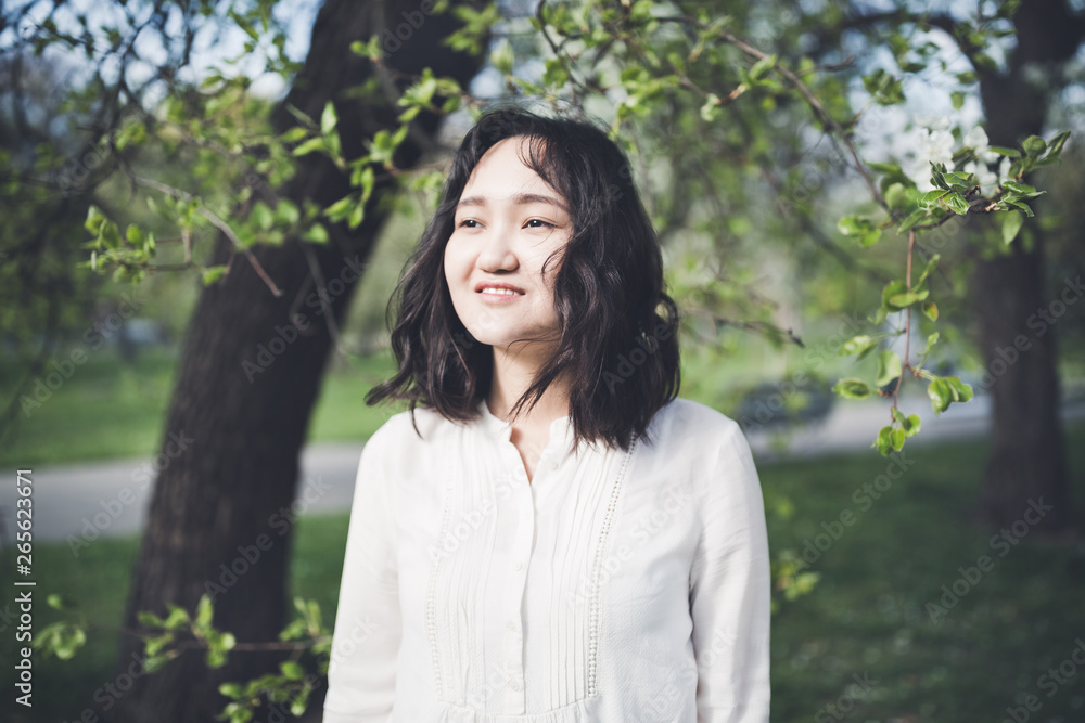 Optimistic young woman in a white blouse in a park. Springtime Optimistic young woman in a white blouse in a park. Springtime