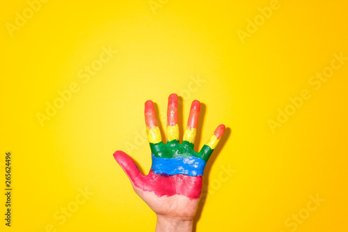 LGBT flag painted on hands on yellow background