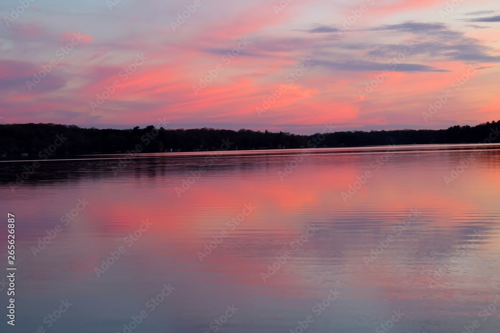 Beautiful pink sunset reflecting on calm lake water. Beautiful pink sunset reflecting on calm lake water.