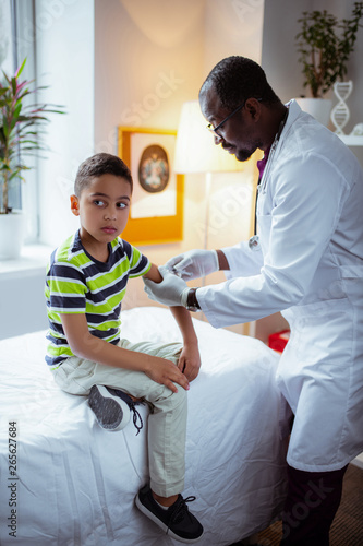 Boy feeling scared before injection while visiting doctor photo