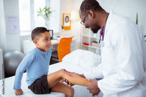 Cute little boy visiting pediatrician after scratching his leg