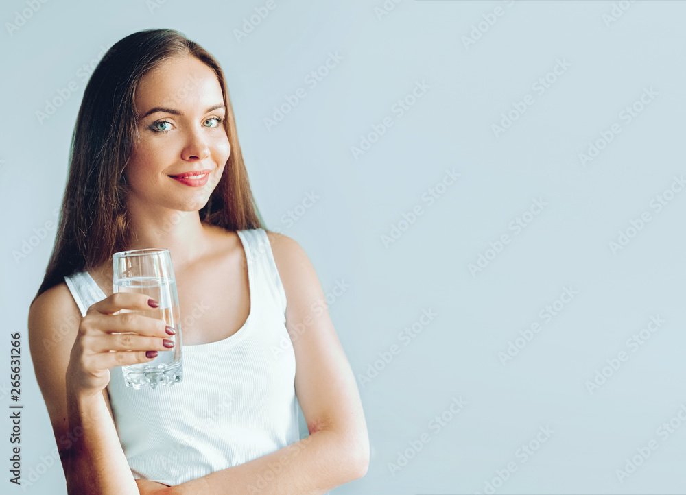 Healthy lifestyle. Young woman show glass of water. Girl drinks water. Portrait of happy smiling female model holding transparent glass of water. Health,Beauty, Diet concept Healthy lifestyle. Young woman show glass of water. Girl drinks water. Portrait of happy smiling female model holding transparent glass of water. Health,Beauty, Diet concept