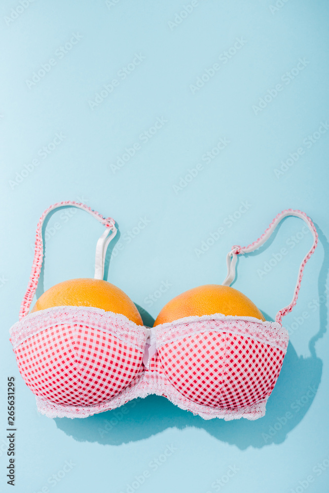 top view of bra with two oranges on blue with copy space, breasts concept